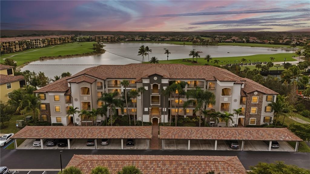 Aerial view at dusk of a water view, a view of apartment building / complex, and view of golf course