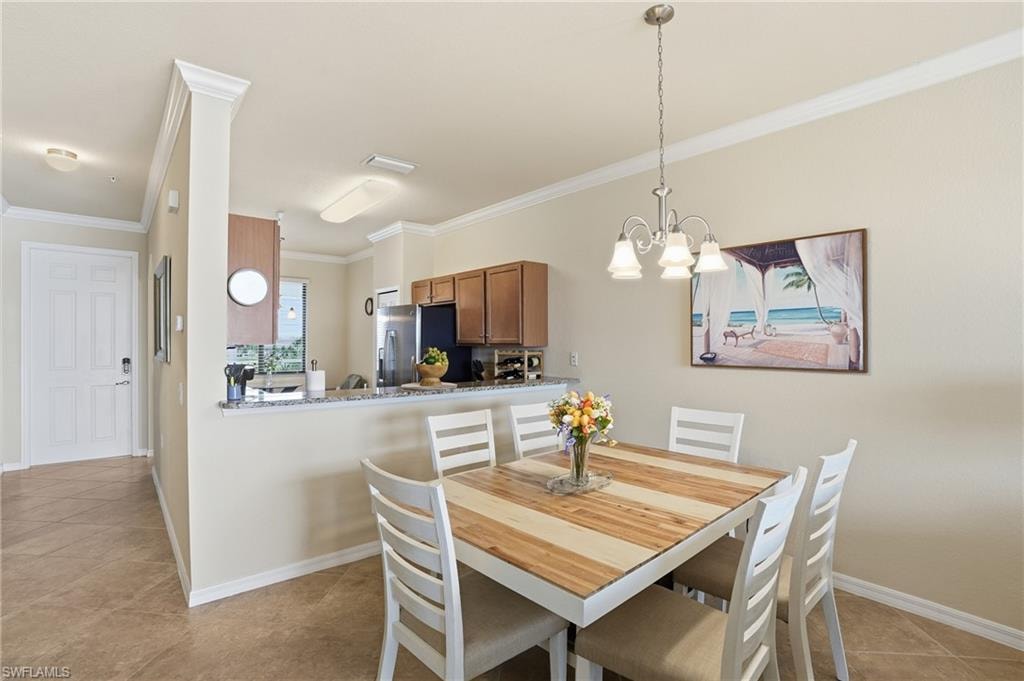 Dining room with light tile patterned flooring, crown molding, and a chandelier