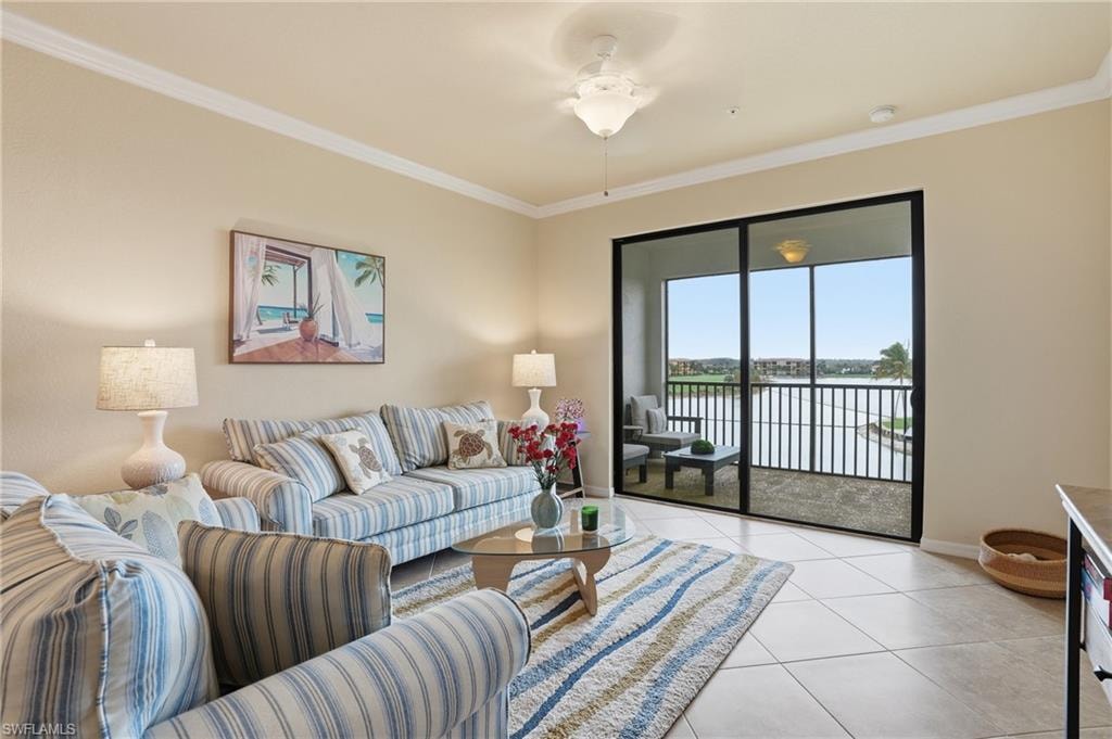 Living room featuring a water view, ornamental molding, light tile patterned floors, and ceiling fan