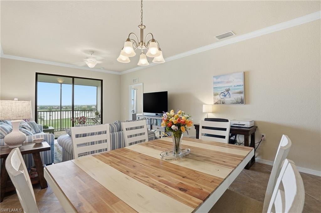 Dining space featuring crown molding, dark tile patterned floors, and a chandelier