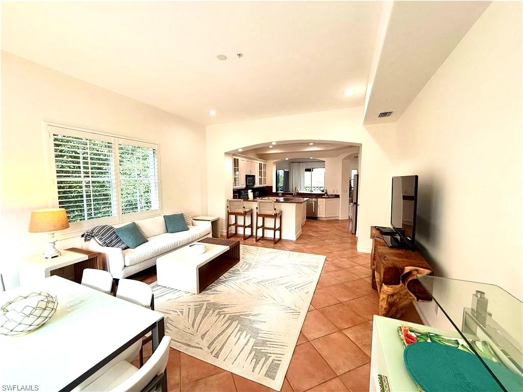Living room featuring arched walkways, light tile patterned flooring, and recessed lighting