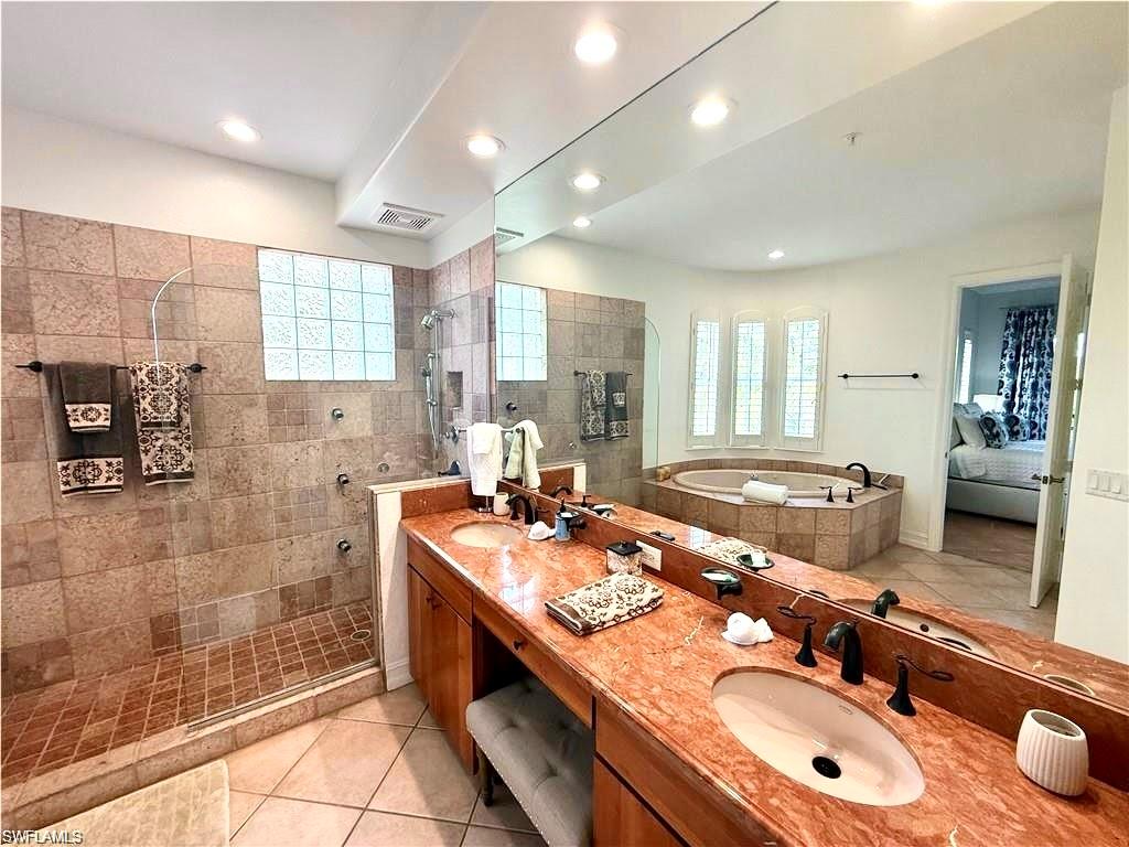 Ensuite bathroom featuring light tile patterned flooring, double vanity, walk in shower, a bath, and recessed lighting