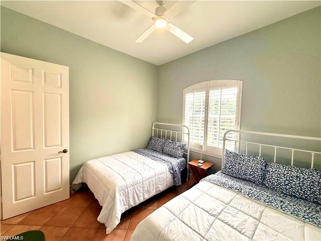 Tiled bedroom with a ceiling fan