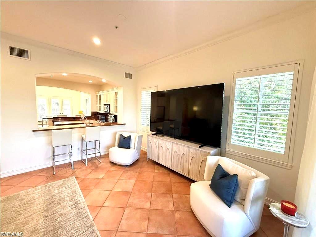 Living room with crown molding, recessed lighting, and light tile patterned floors