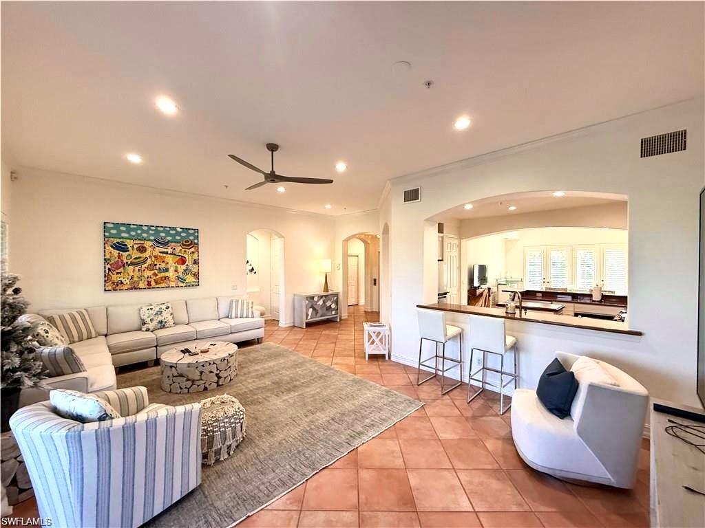 Living room featuring arched walkways, light tile patterned flooring, recessed lighting, ceiling fan, and crown molding