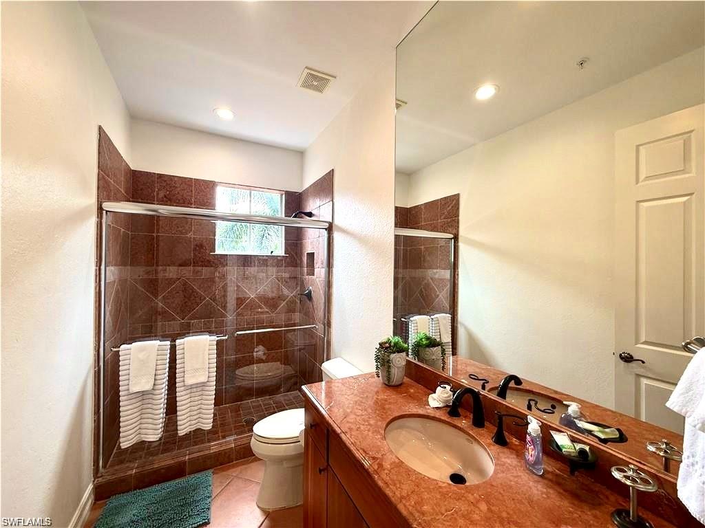 Full bath featuring vanity, a shower stall, light tile patterned floors, and a textured wall