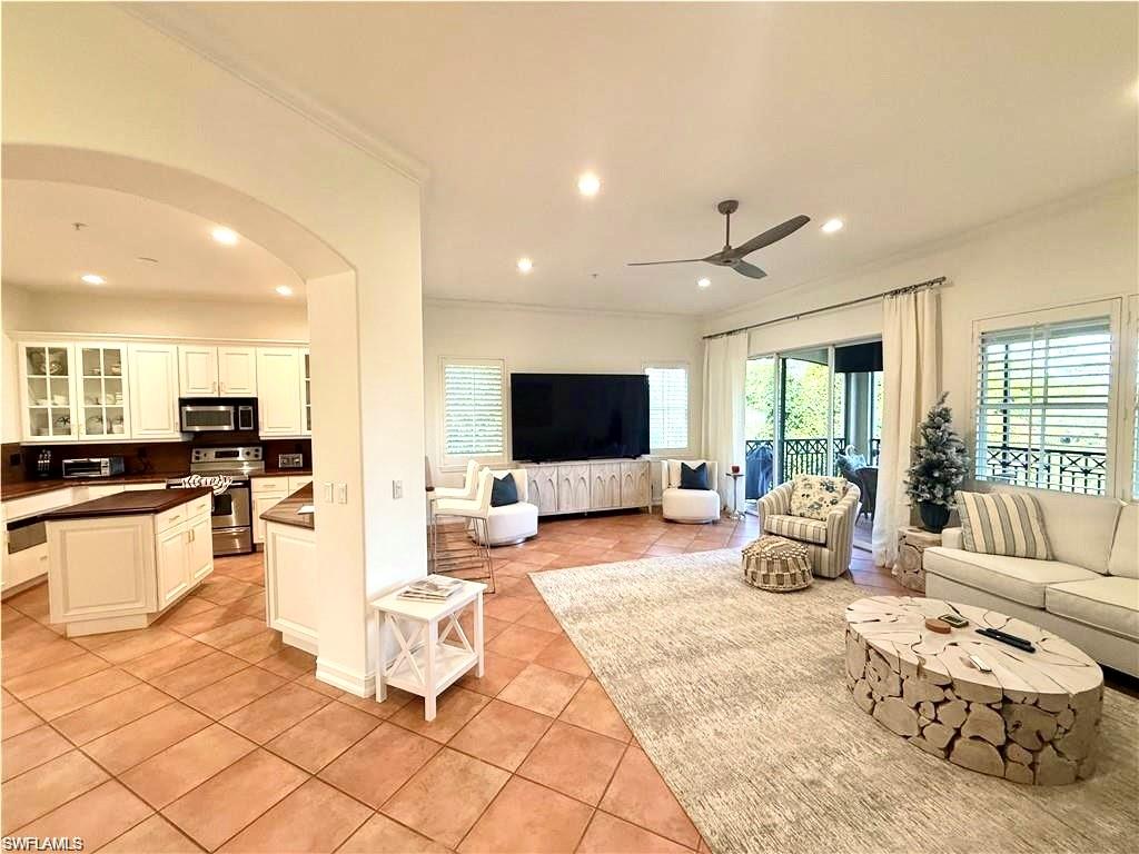 Living room with recessed lighting, arched walkways, light tile patterned floors, crown molding, and ceiling fan