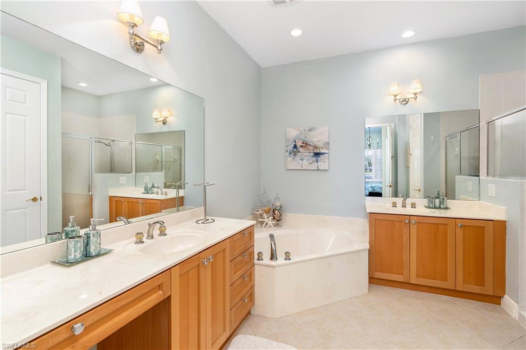 Full bath featuring two vanities, a stall shower, a garden tub, and light tile patterned floors