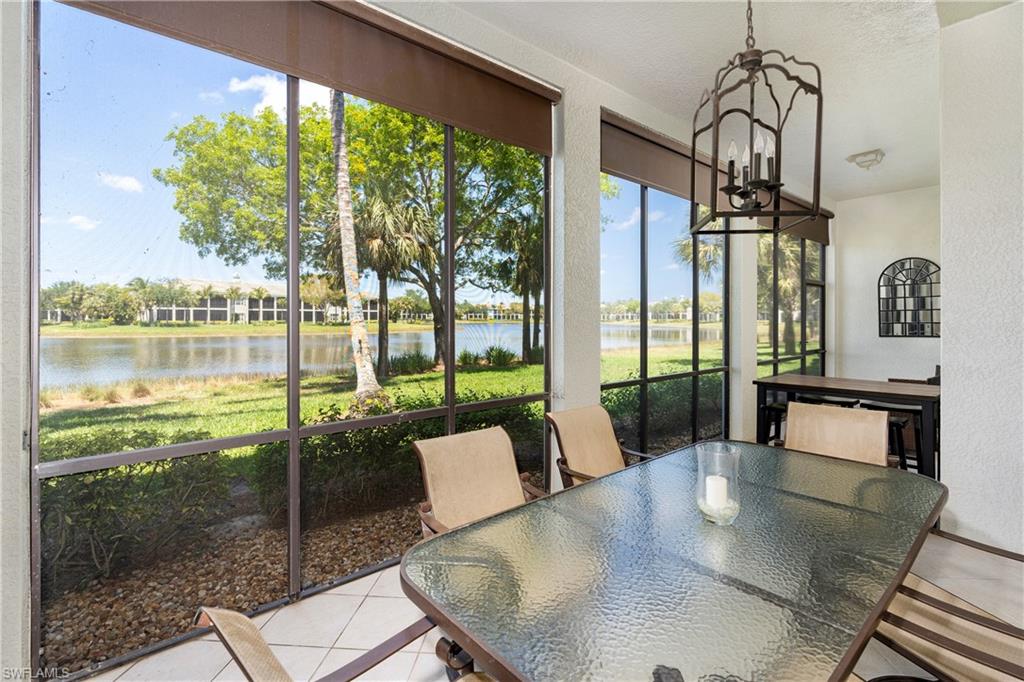 Sunroom featuring a chandelier, tile patterned flooring, a textured wall, and a water view