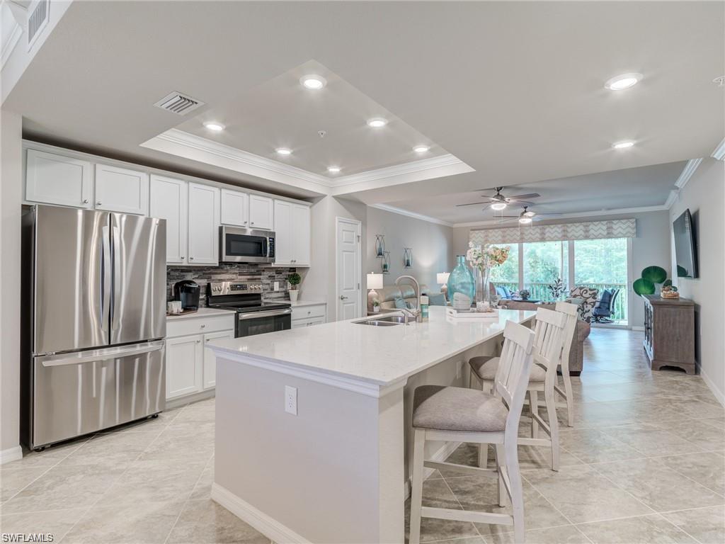 Kitchen featuring a center island with sink, white cabinets, sink, a kitchen bar, and stainless steel appliances
