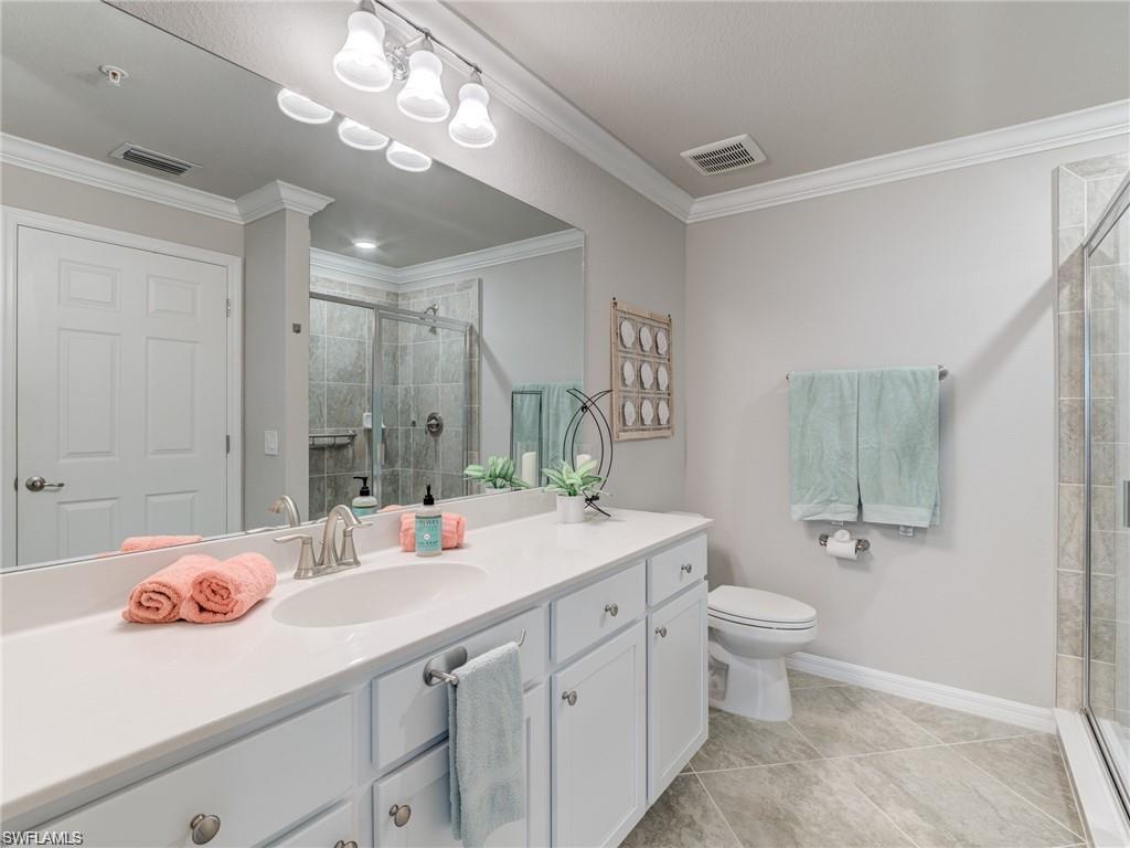 Bathroom with tile patterned flooring, vanity, a shower with shower door, and crown molding