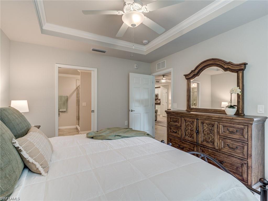 Bedroom with ensuite bathroom, a raised ceiling, ceiling fan, and ornamental molding