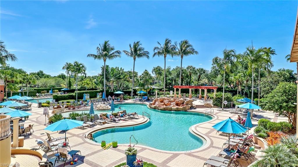 Community pool with a patio and view of wooded area