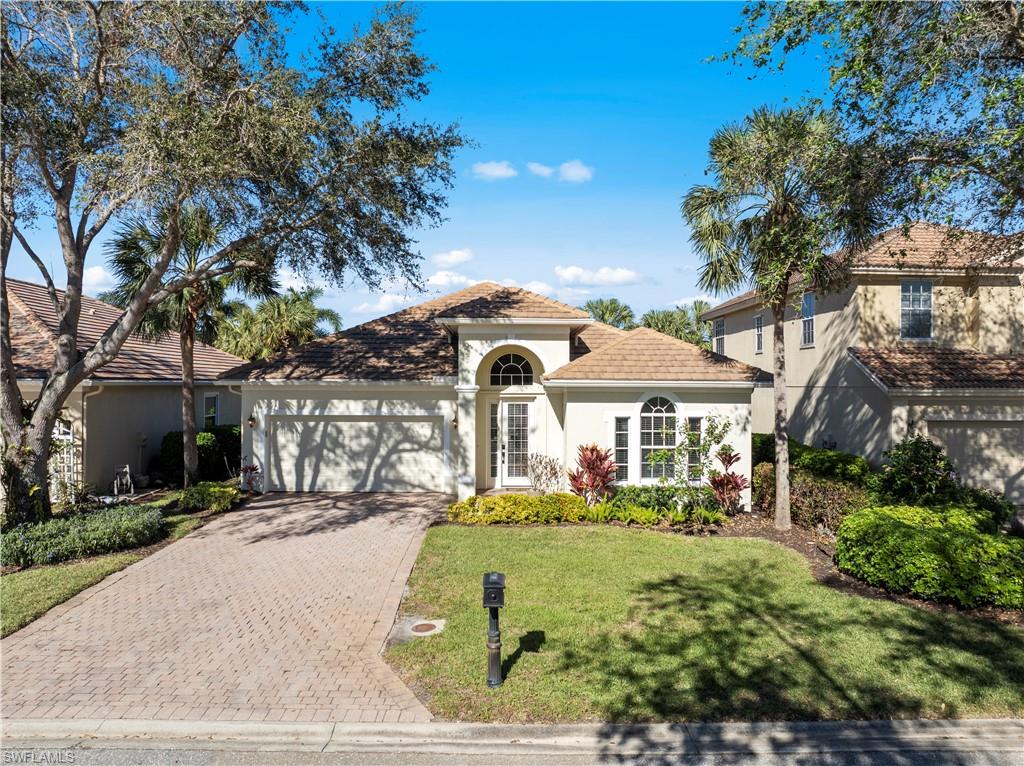 Mediterranean / spanish home featuring stucco siding, decorative driveway, a garage, a front yard, and a tiled roof