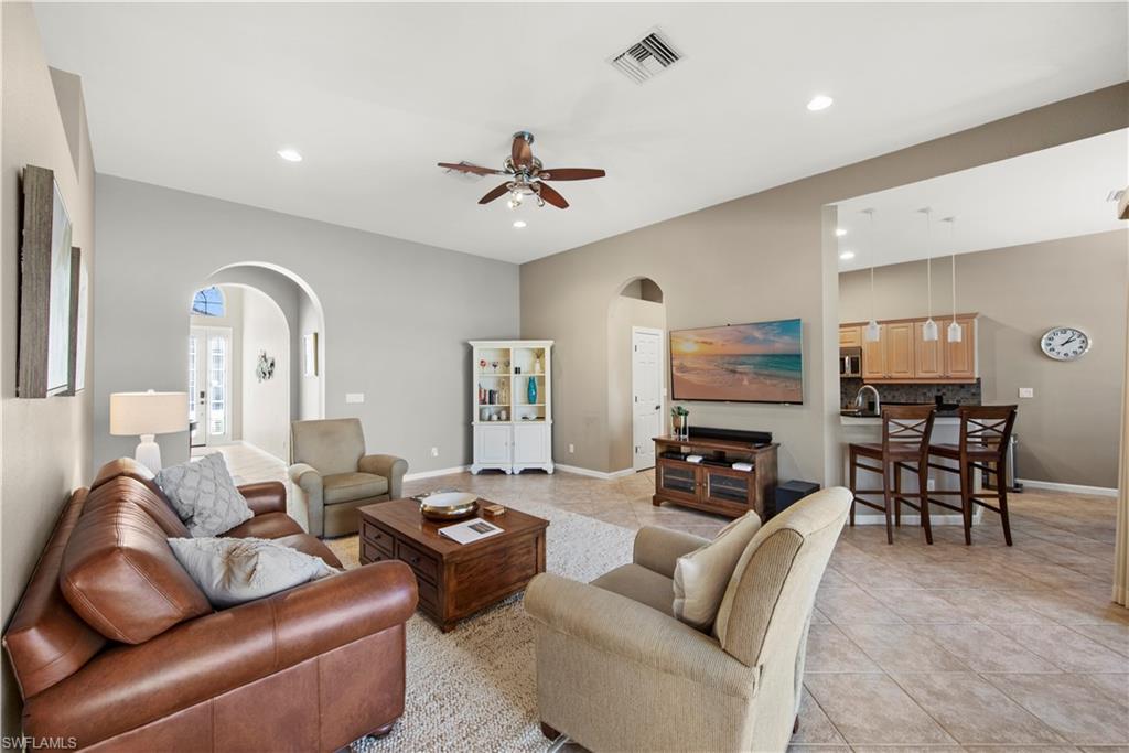 Living room featuring arched walkways, light tile patterned flooring, ceiling fan, and recessed lighting