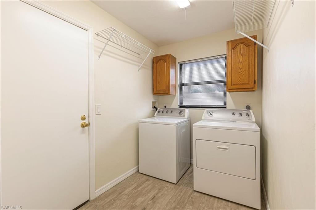Laundry area featuring separate washer and dryer, light wood-type flooring, and cabinet space