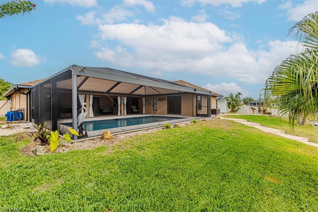 Back of property featuring a sunroom, glass enclosure, an outdoor pool, a lawn, and a patio area