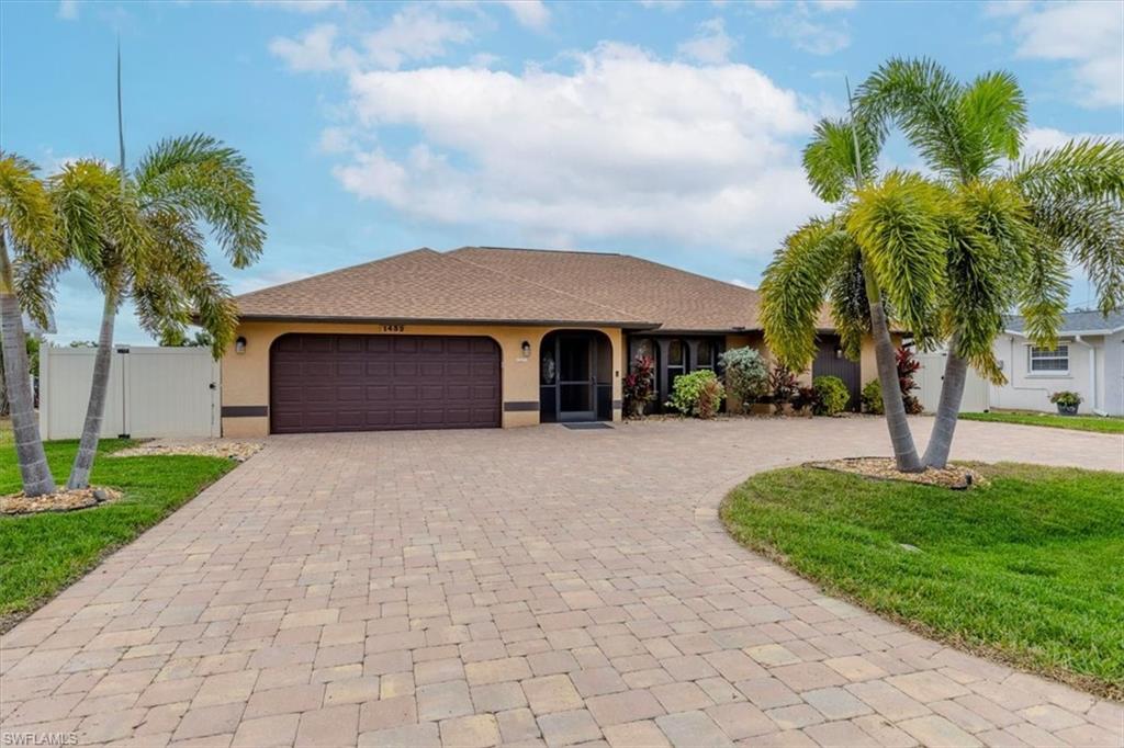 Ranch-style home with curved driveway, stucco siding, an attached garage, and a gate