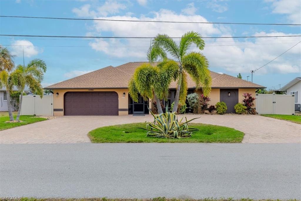View of front of house with decorative driveway, stucco siding, a gate, and roof with shingles