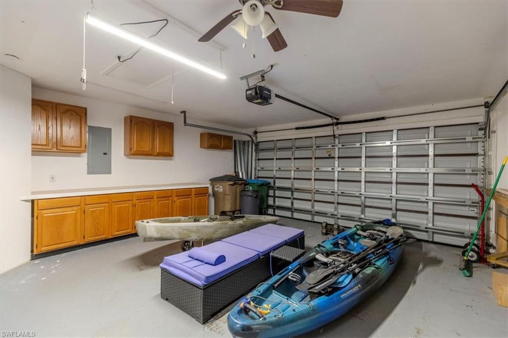 Garage featuring electric panel, a ceiling fan, and a garage door opener