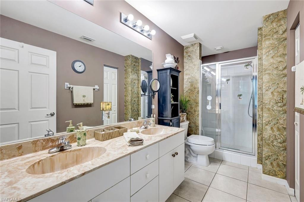 Bathroom featuring double vanity, a shower stall, and light tile patterned flooring