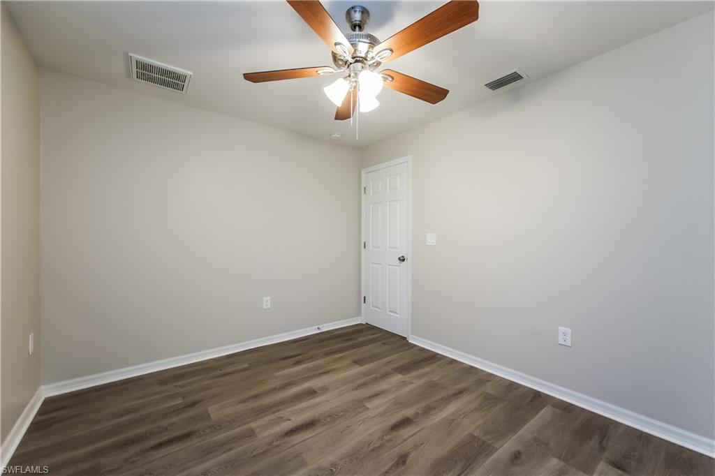 Unfurnished room with dark wood-style flooring and a ceiling fan