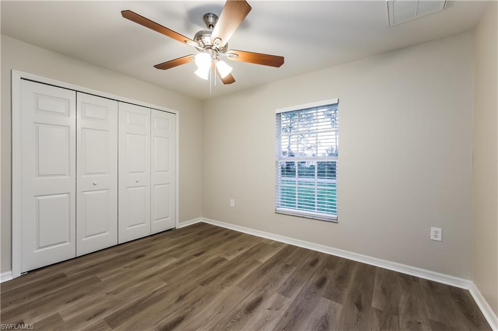 Unfurnished bedroom featuring dark wood-style floors, a closet, and a ceiling fan
