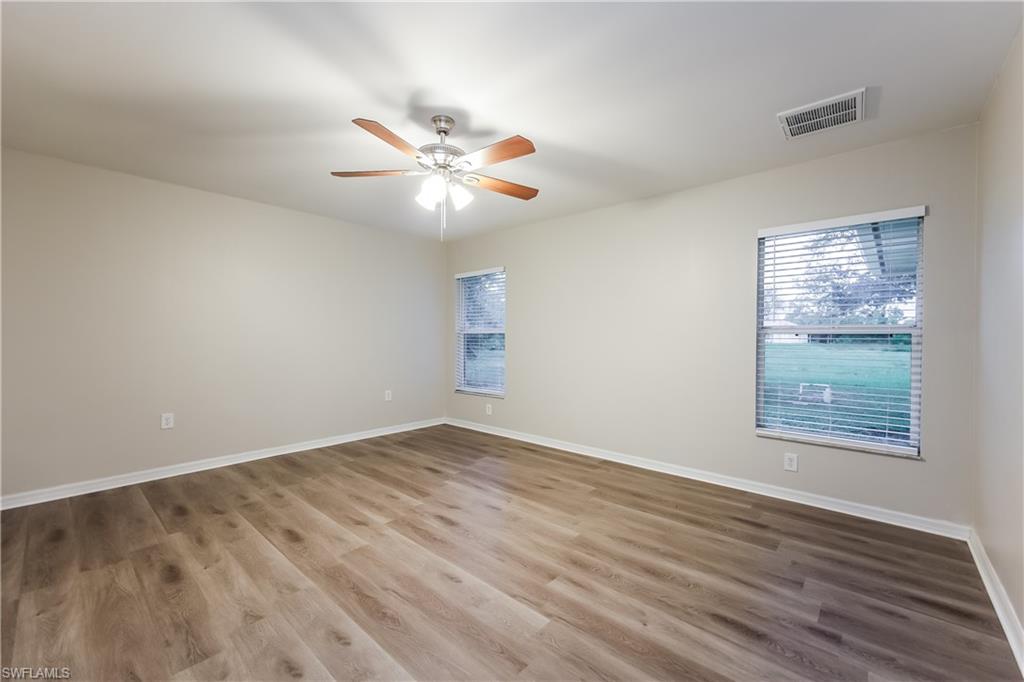 Spare room with wood finished floors, plenty of natural light, and ceiling fan