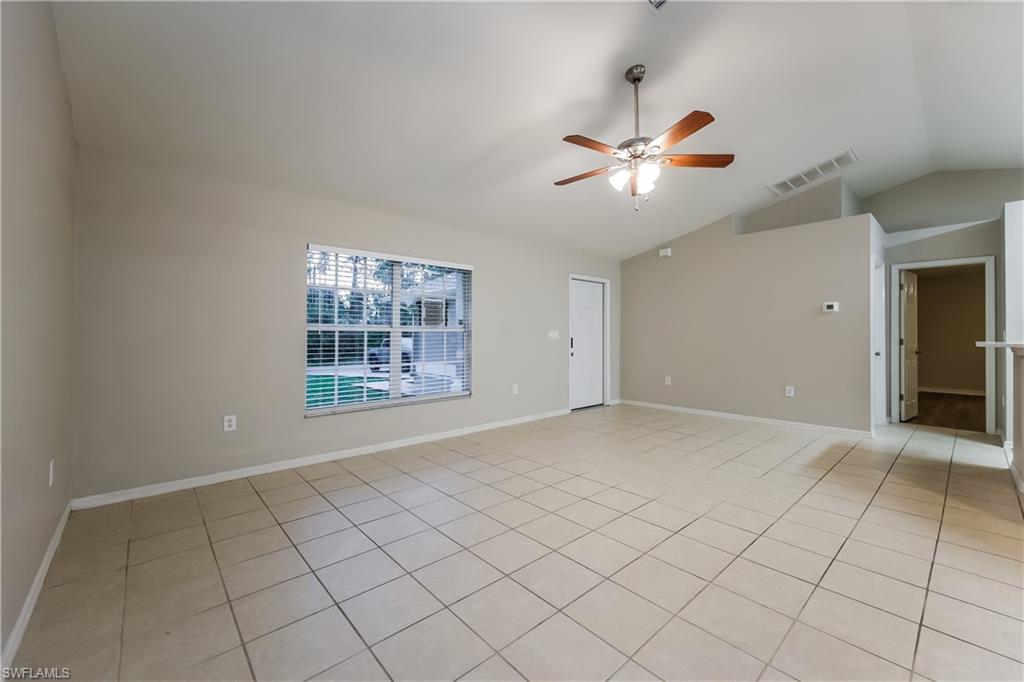 Spare room with lofted ceiling, a ceiling fan, and light tile patterned flooring