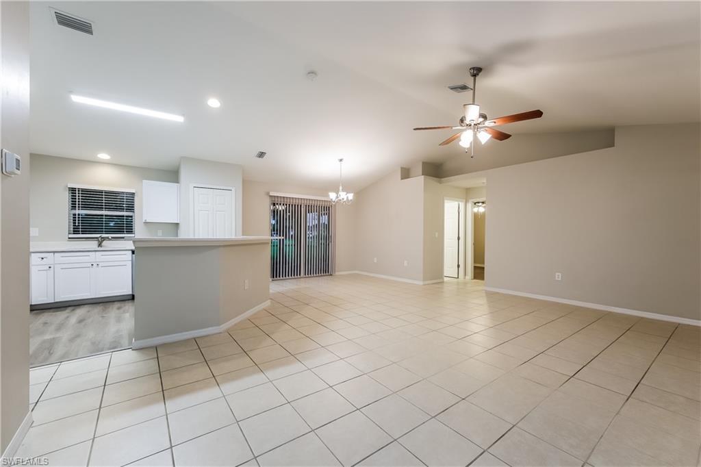Kitchen with white cabinetry, light countertops, a chandelier, lofted ceiling, and light tile patterned floors