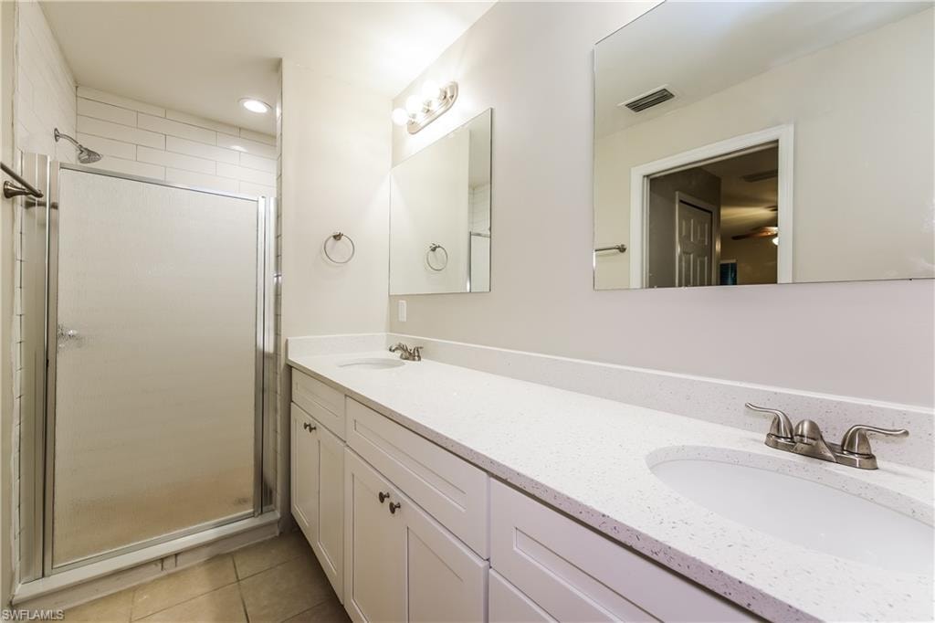 Bathroom featuring double vanity, a shower stall, light tile patterned floors, recessed lighting, and a ceiling fan