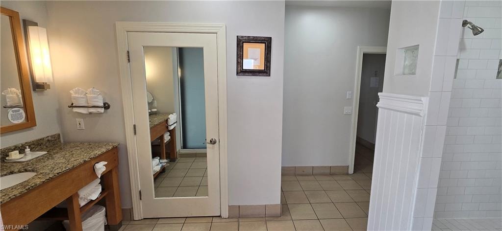 Full bathroom featuring a tile shower, light tile patterned floors, and vanity