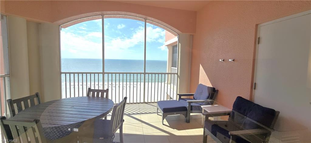 Dining space with view of water and beach, a textured wall, healthy amount of natural light, and light tile patterned flooring