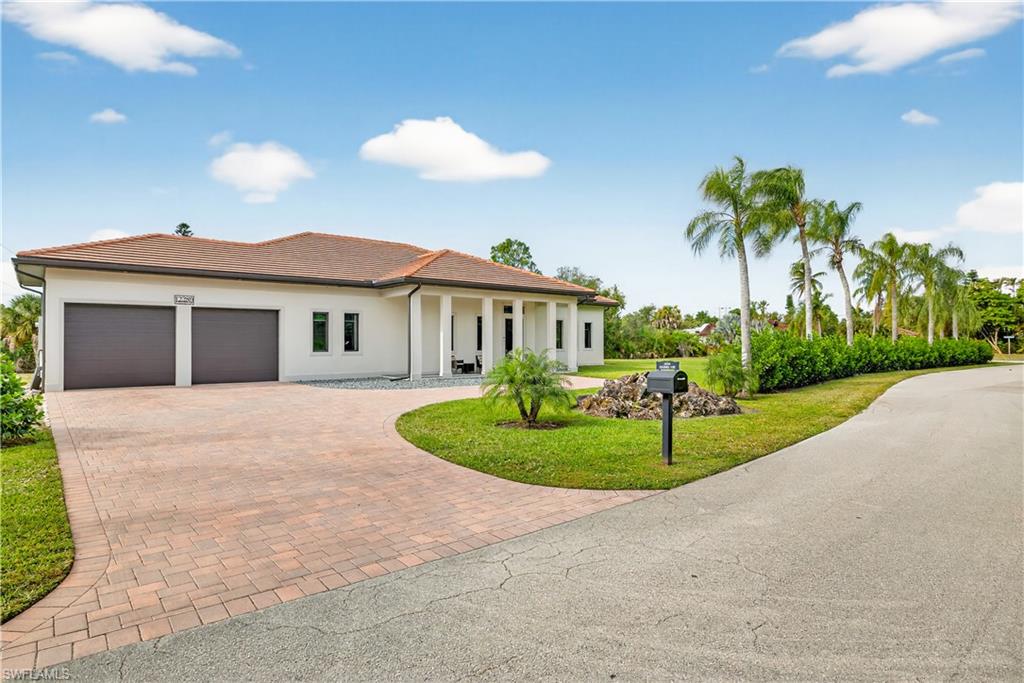 Mediterranean / spanish-style house with a front yard, decorative driveway, a garage, stucco siding, and a porch