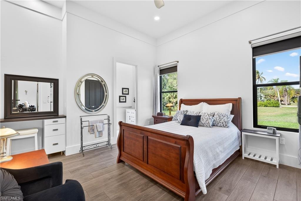 Bedroom featuring light wood-style flooring, connected bathroom, a ceiling fan, and recessed lighting