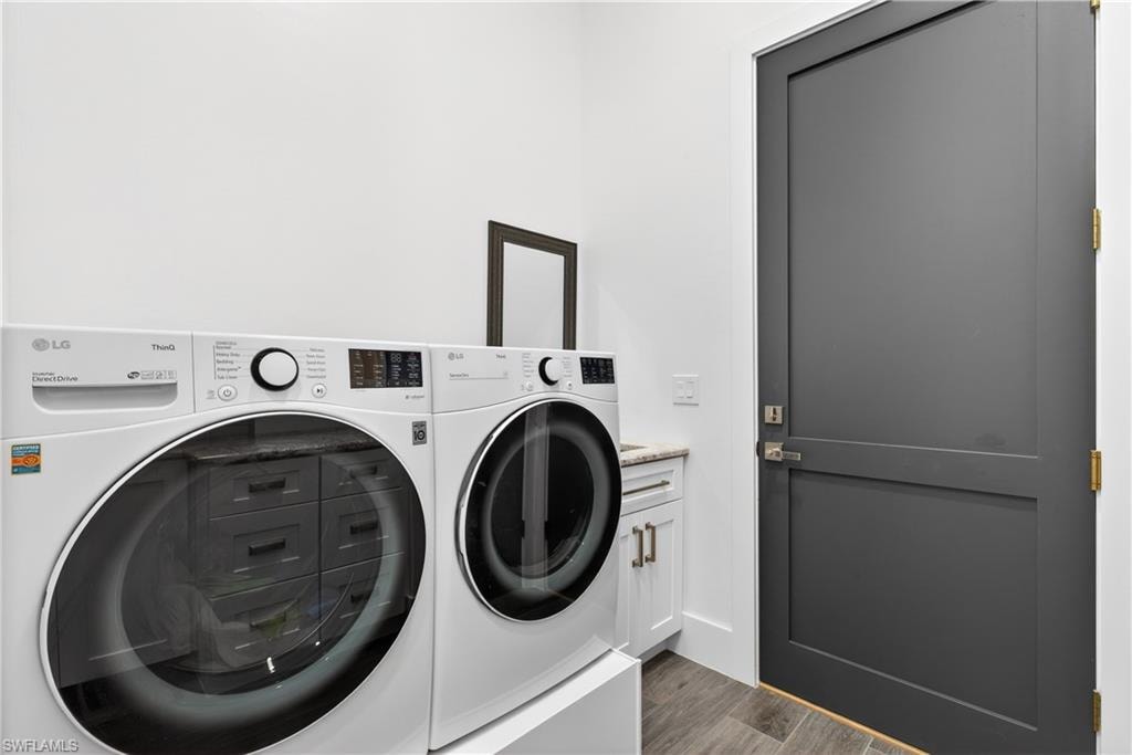 Laundry area with washing machine and clothes dryer, dark wood-style flooring, and cabinet space