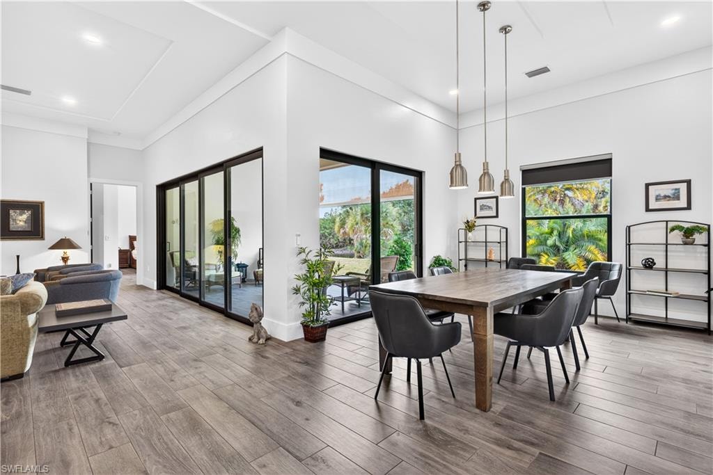 Dining space with light wood finished floors, healthy amount of natural light, recessed lighting, and a high ceiling