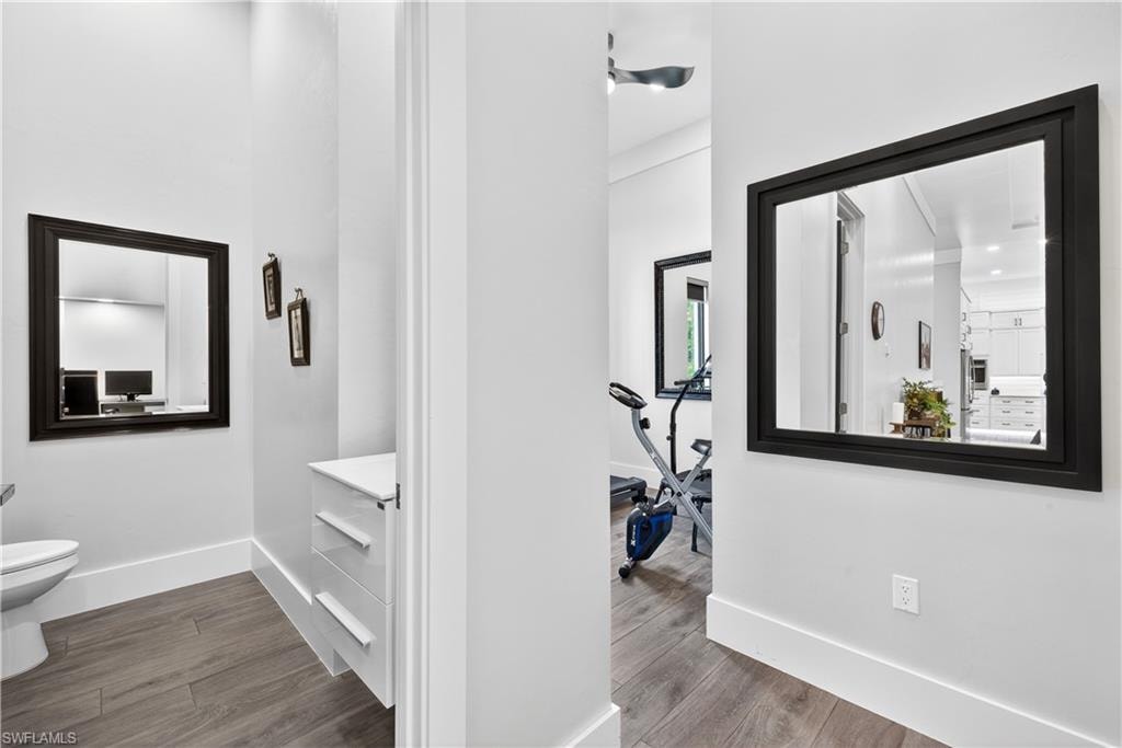 Corridor featuring dark wood-style flooring and baseboards
