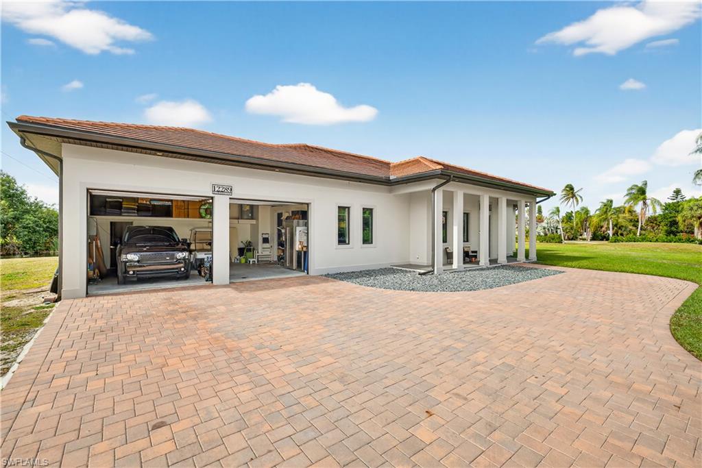 Front of property with decorative driveway, an attached garage, stucco siding, a yard, and a tile roof