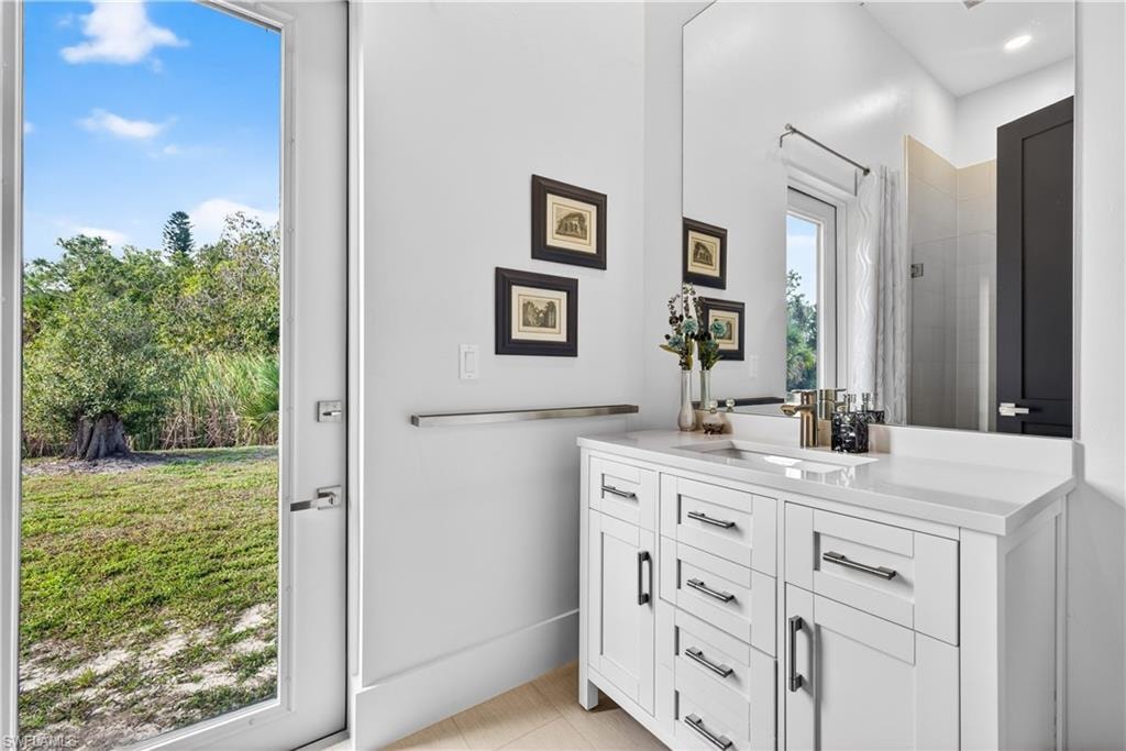 Bathroom with vanity, tiled shower, and light tile patterned flooring