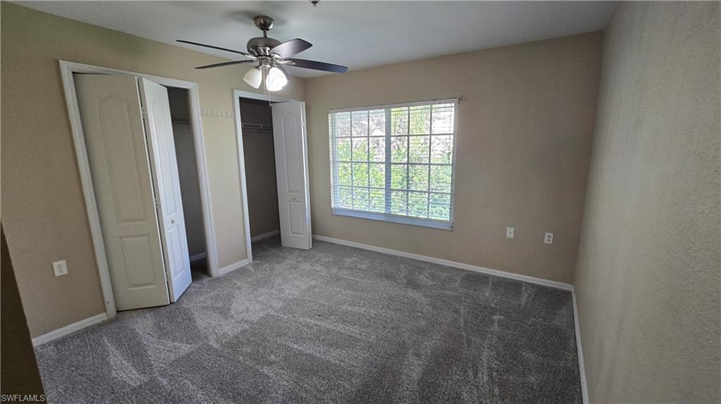 Unfurnished bedroom with two closets, carpet floors, and ceiling fan