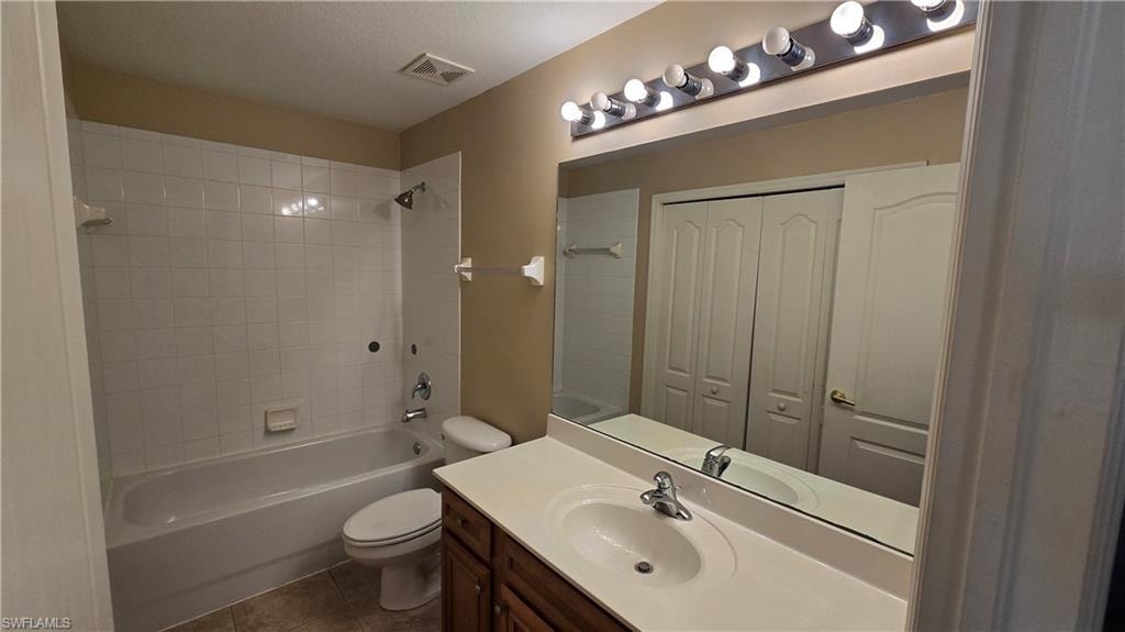 Bathroom featuring bathtub / shower combination, vanity, a closet, and dark tile patterned floors