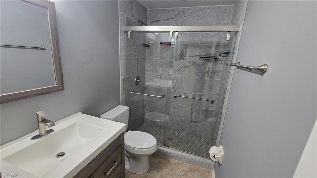 Full bathroom with vanity, a stall shower, and light tile patterned flooring