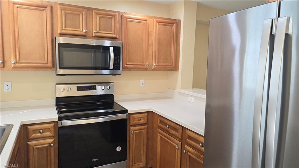 Kitchen with appliances with stainless steel finishes, light countertops, and brown cabinets