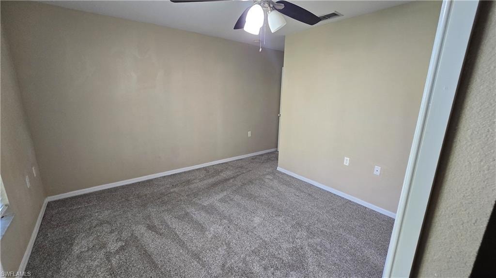 Carpeted spare room with baseboards and a ceiling fan
