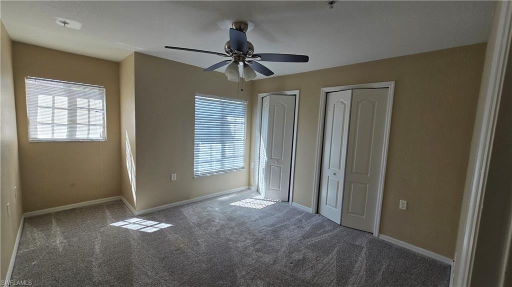 Unfurnished bedroom featuring two closets, multiple windows, and carpet flooring