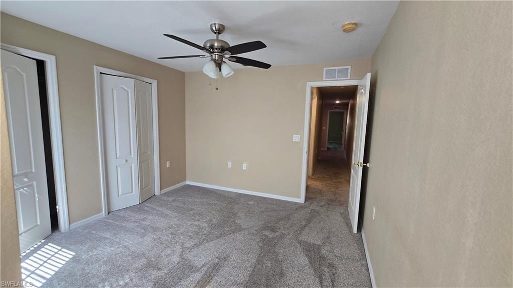 Unfurnished bedroom with carpet floors, a ceiling fan, and multiple closets