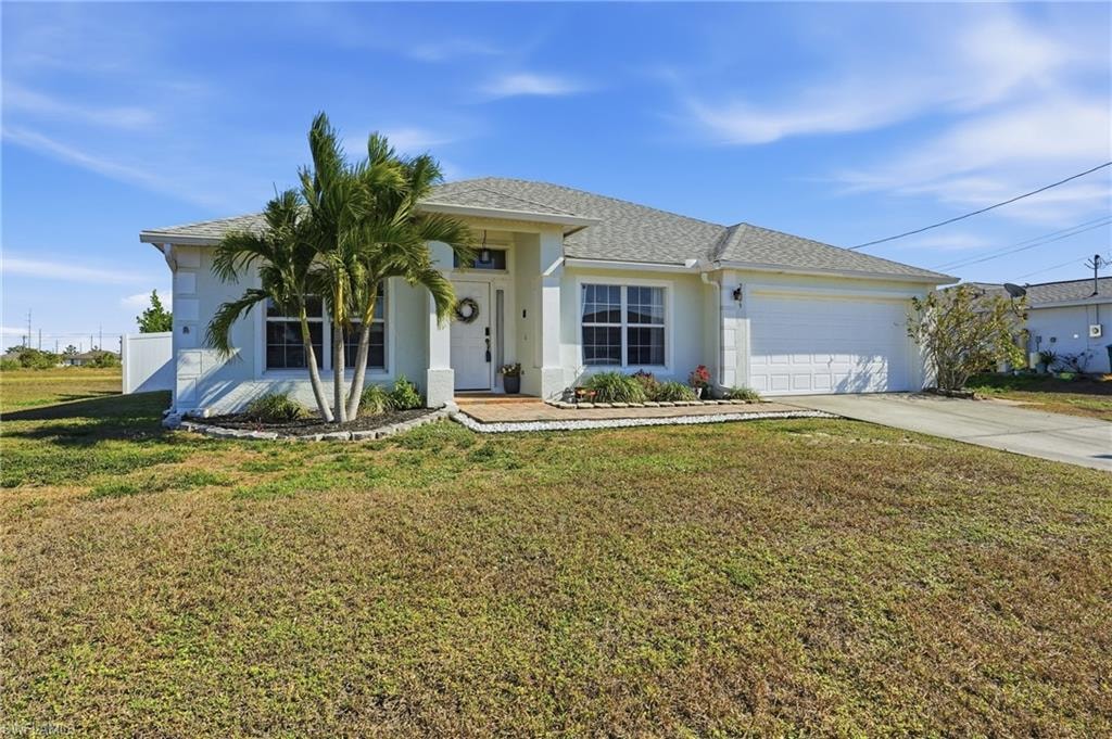 View of front of house featuring a front yard, concrete driveway, stucco siding, and a shingled roof