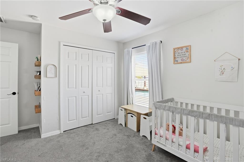 Bedroom with carpet, a closet, a ceiling fan, and a nursery area