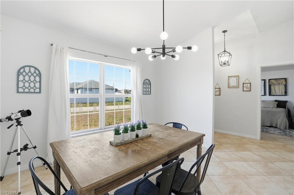 Dining space with light tile patterned floors, a chandelier, and lofted ceiling